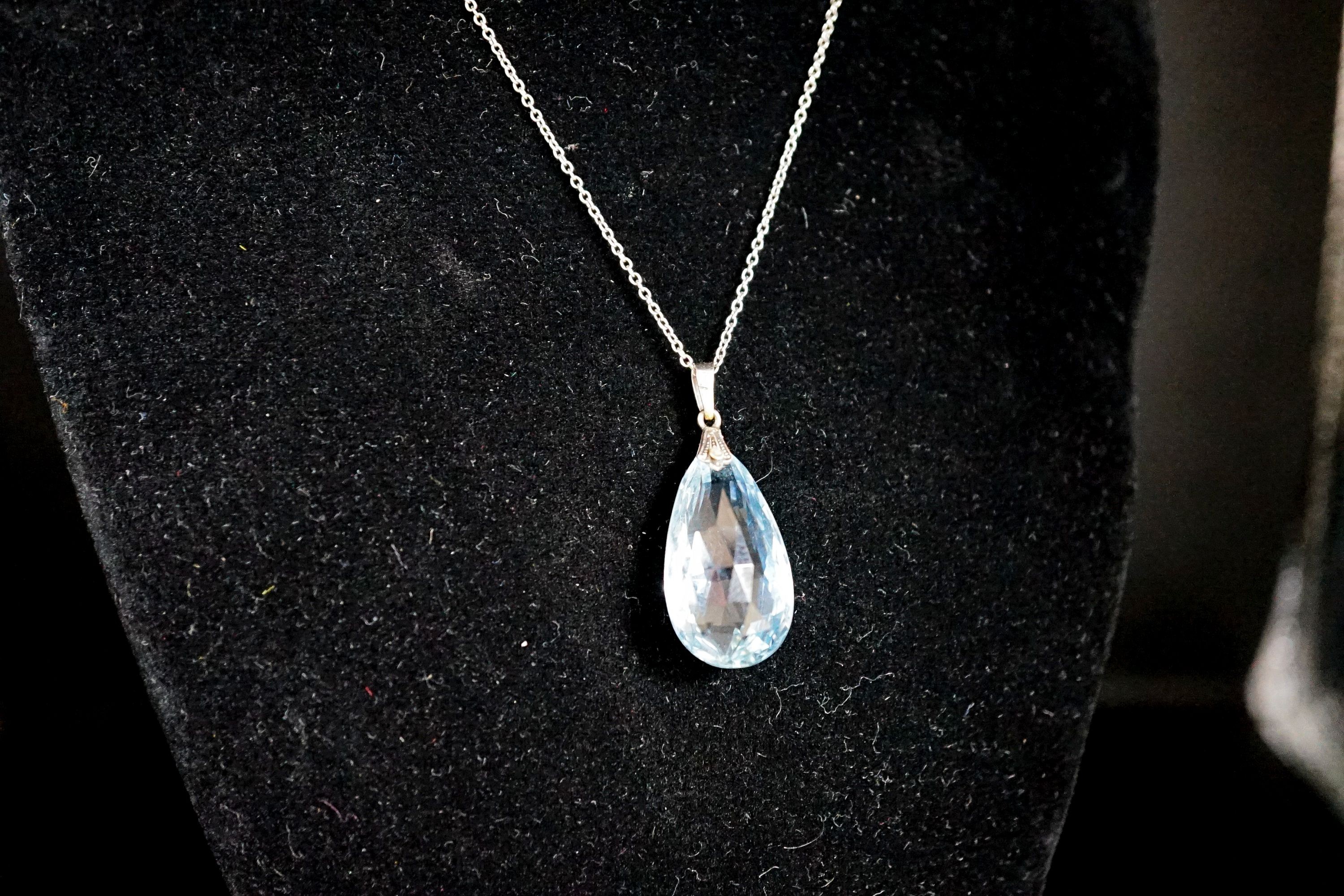 An 18ct mounted facetted pear cut aquamarine set pendant, 33mm, on a 375 white metal fine link chain, 45cm, gross weight 5.2 grams.